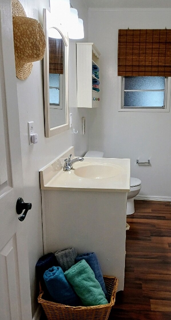 Une salle de bain équipée d’un lavabo, de toilettes et d’un panier en osier contenant des serviettes.