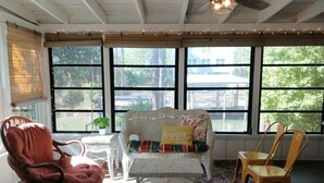 Habitació il·luminada pel sol amb mobles de vimet, un ventilador de sostre i grans finestres que donen a l'exterior.