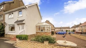 A residential area with houses, a driveway, and a garden. - Beautiful Three Bedroom Seaside Retreat (Prestonpans)