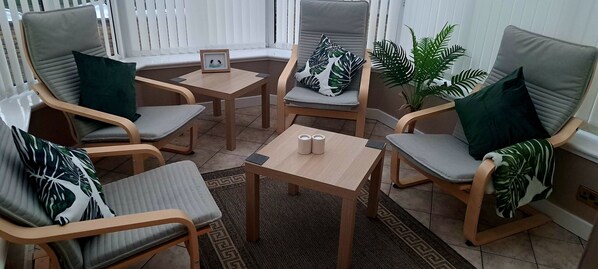 A cozy seating area with wooden chairs and a small table, featuring a framed picture and a potted plant. - Beautiful Three Bedroom Seaside Retreat (Prestonpans)