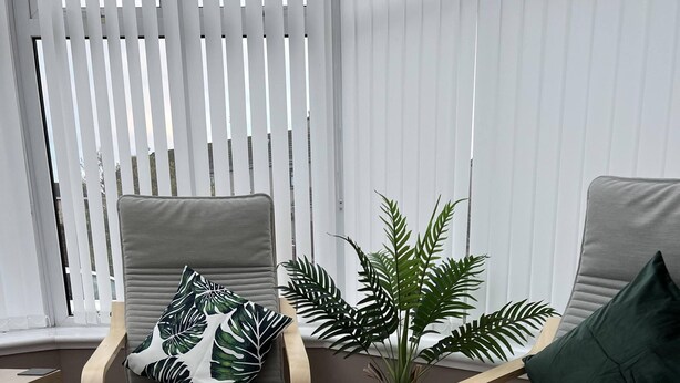 A modern living room with two grey armchairs, a wooden coffee table, and a potted plant. - Beautiful Three Bedroom Seaside Retreat (Prestonpans)