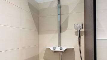 A shower with a handheld showerhead and a fixed overhead showerhead in a tiled bathroom.