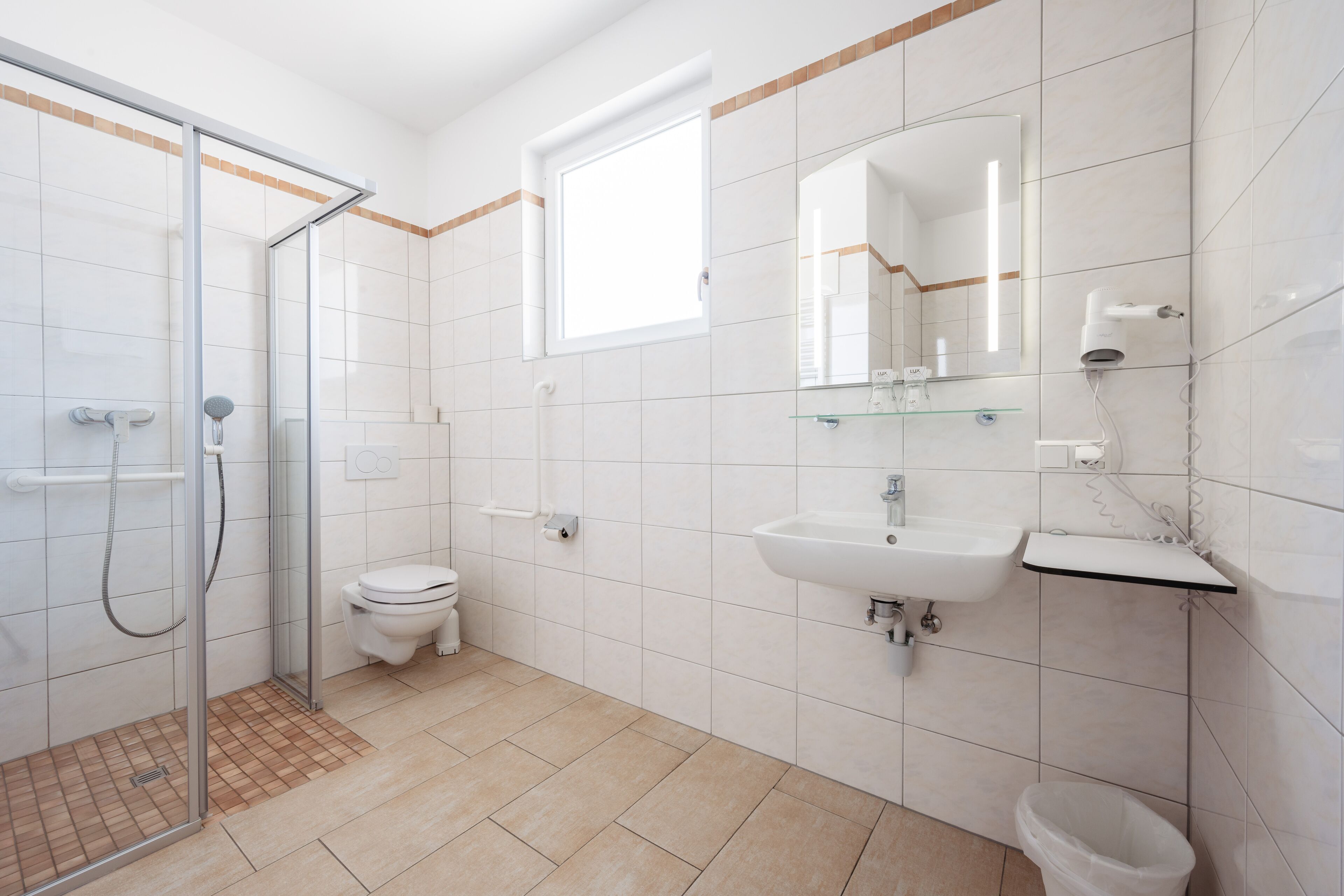 Un baño moderno con cabina de ducha de vidrio, inodoro, lavabo y espejo.
