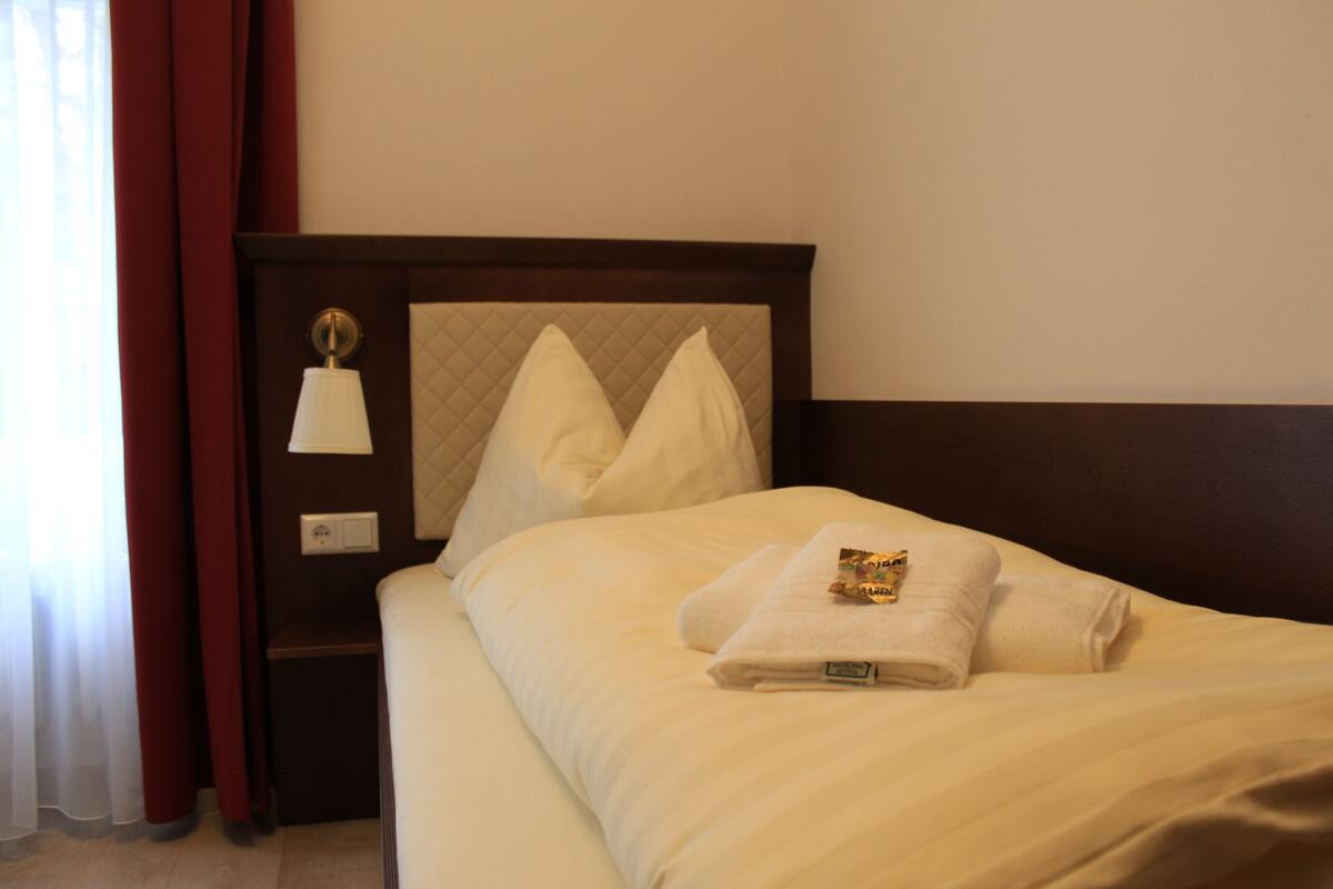 Una cama bien hecha con una almohada y una toalla doblada.