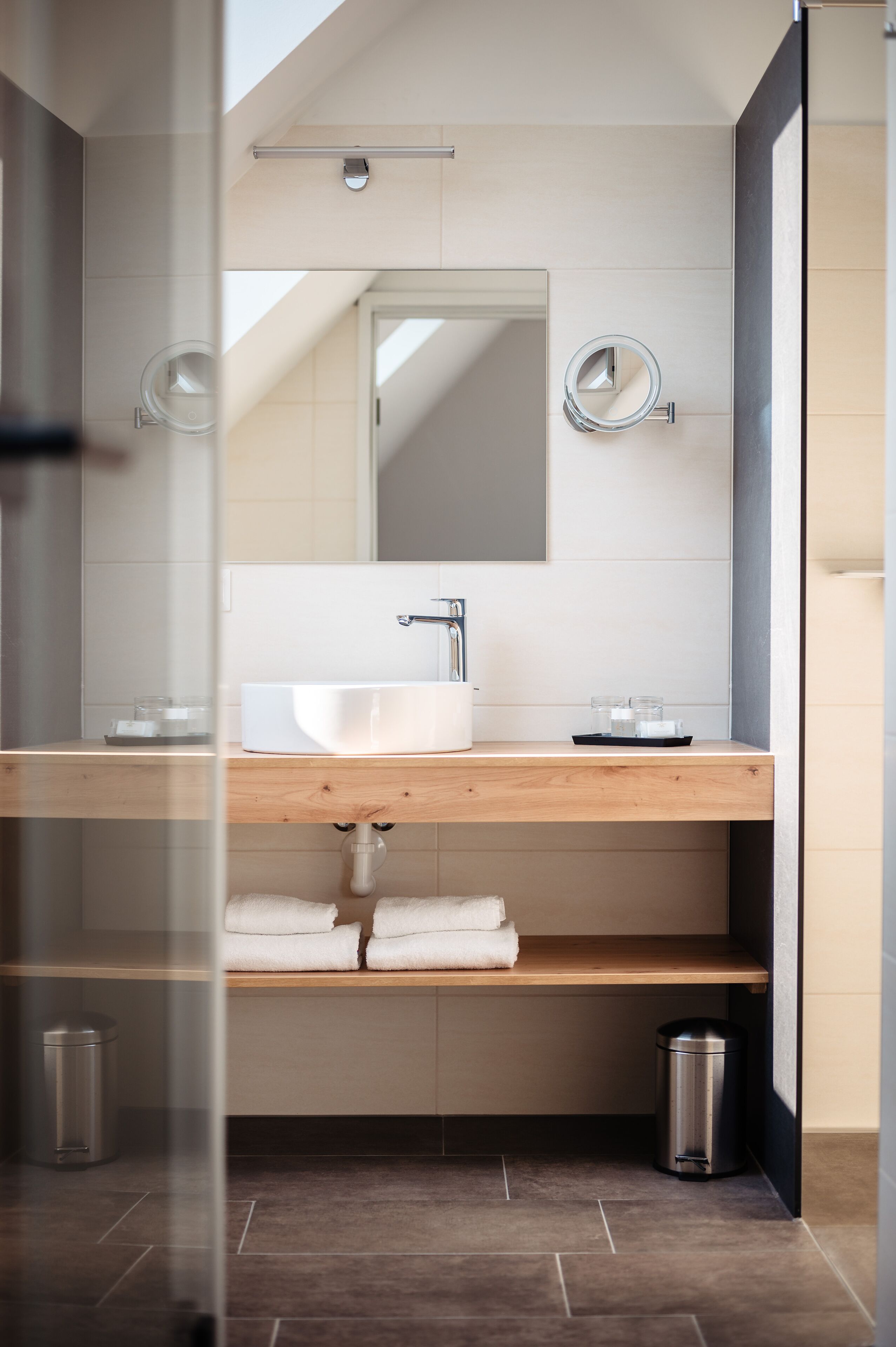 Une salle de bain moderne avec un meuble-lavabo en bois, un grand miroir et un lavabo blanc.