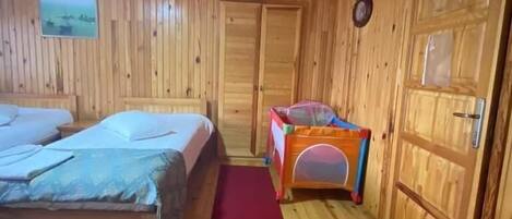 A wooden room with two beds, a red carpet, and a small play area.