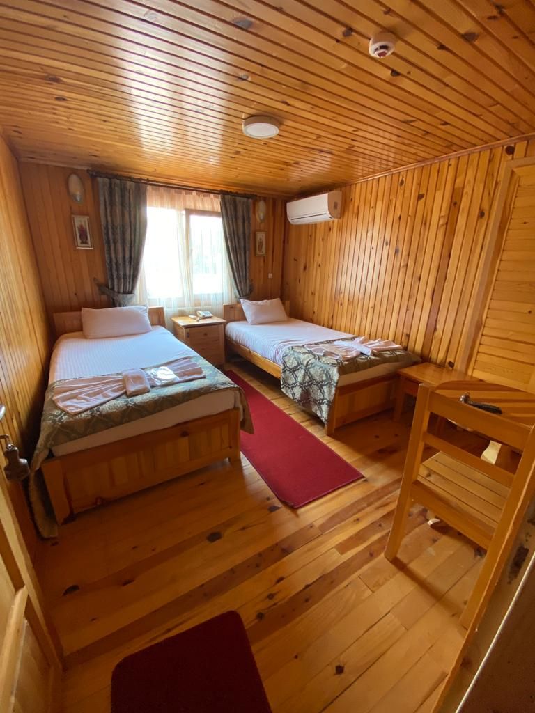 A cabin with two wooden beds, a red rug, and a wooden chair.