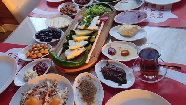 Una mesa dispuesta para una comida, con diferentes platos, incluyendo pan, huevos y una bebida.