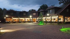 Un hotel con un patio empedrado, zona de estar al aire libre y varias construcciones con ventanas amplias.