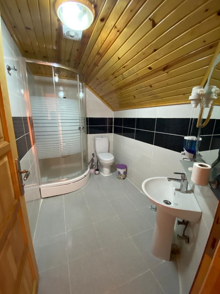 A bathroom with a shower, toilet, sink, and tiled walls.