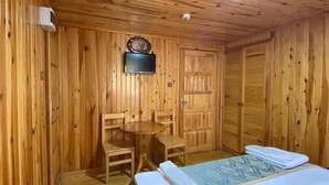 Una habitación con paneles de madera, una cama, una mesita y dos sillas.