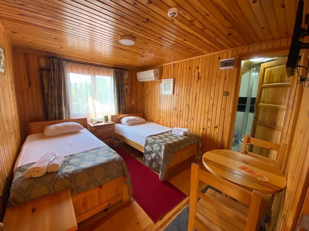 A cabin with two wooden beds, a small table, and a chair.
