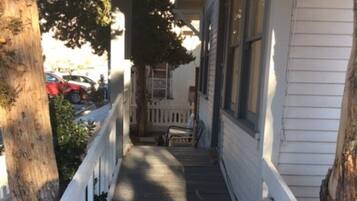 A wooden porch with a white railing, leading to a house entrance.