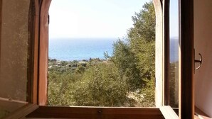 A room with a large arched window overlooking a coastal landscape. - Villa with sea view (Torre Delle Stelle (Maracalagonis))