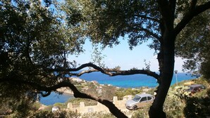 A coastal landscape with a tree in the foreground, a road, and a car parked on the side. - Villa with sea view (Torre Delle Stelle (Maracalagonis))