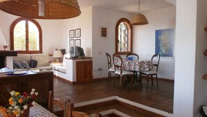 A cozy living room with a sofa, TV, and a dining area with a table and chairs. - Villa with sea view (Torre Delle Stelle (Maracalagonis))
