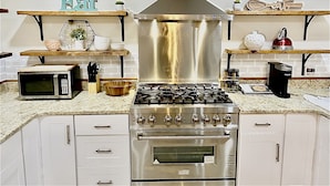 Een moderne keuken met een kookplaat, oven, magnetron en diverse keukengerei.