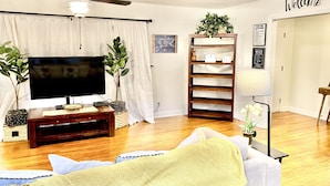 Een woonkamer met een flatscreen-tv, plafondventilator en een 'Welcome'-bord aan de muur.
