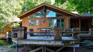 A wooden cabin with a deck, a table, and chairs. - Luxury Cabin with Indoor Heated SaltWater Pool! (Old Forge)