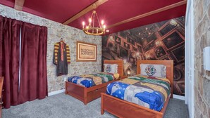 Une chambre à coucher avec deux lits en bois, un mur en pierre, un plafond rouge et une fresque représentant une pièce remplie de divers objets.