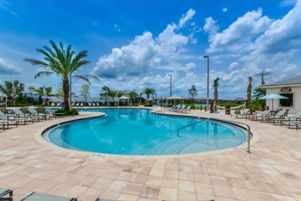 Una piscina con sillones de descanso y palmeras.