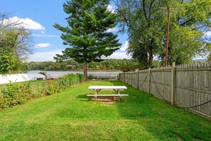 Een gazon met een picknicktafel, een houten omheining en uitzicht op een meer.