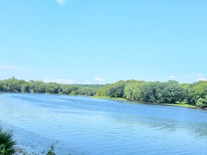 Een rustige rivier met een bebost oever en een heldere lucht.