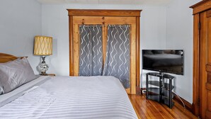 A bedroom with a bed, a TV on a stand, a lamp, and a wooden wardrobe. - Home on the River - stunning views and Comfy Beds (Waterford)