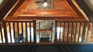 Une chambre mansardée avec un mur en pierre, des poutres en bois et un ventilateur de plafond.