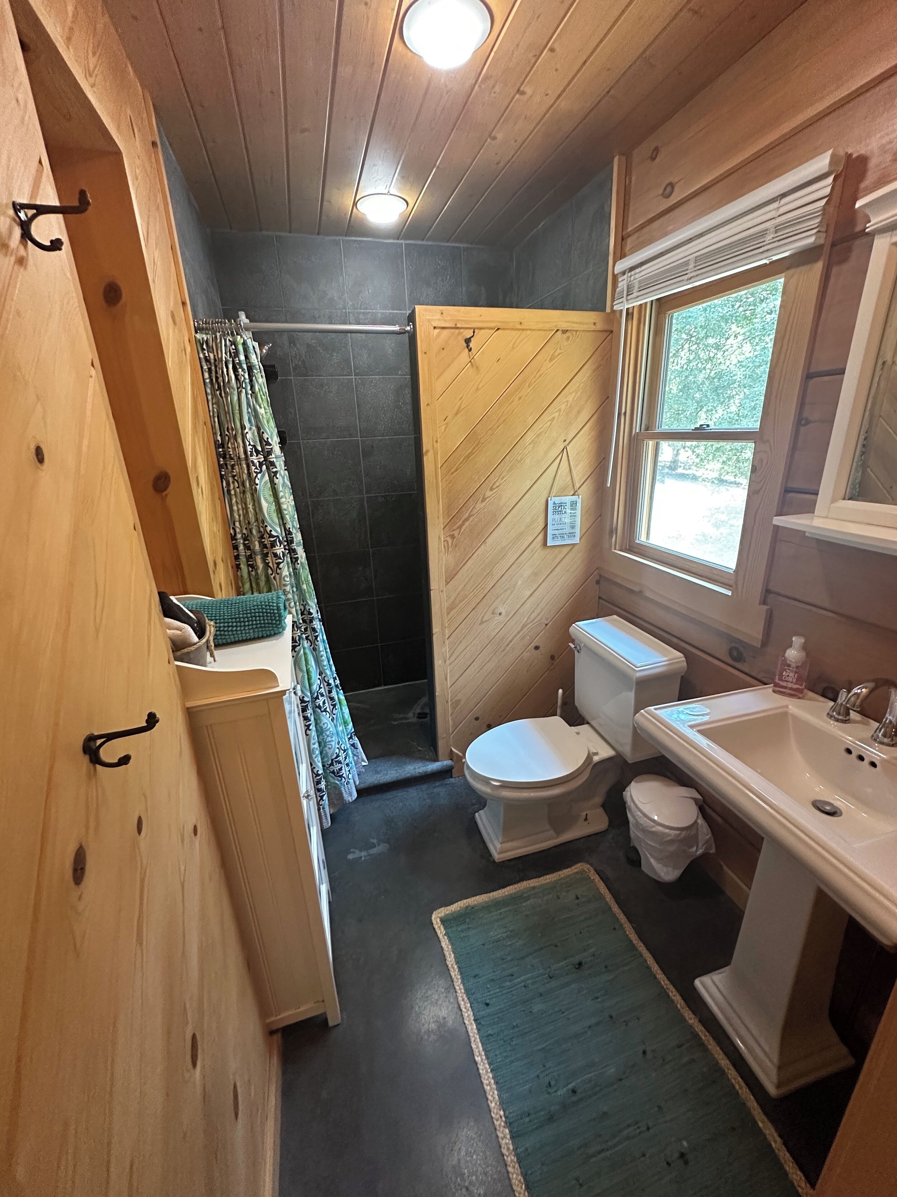 Une petite salle de bain avec un plafond en bois, une zone douche, des toilettes et un lavabo.