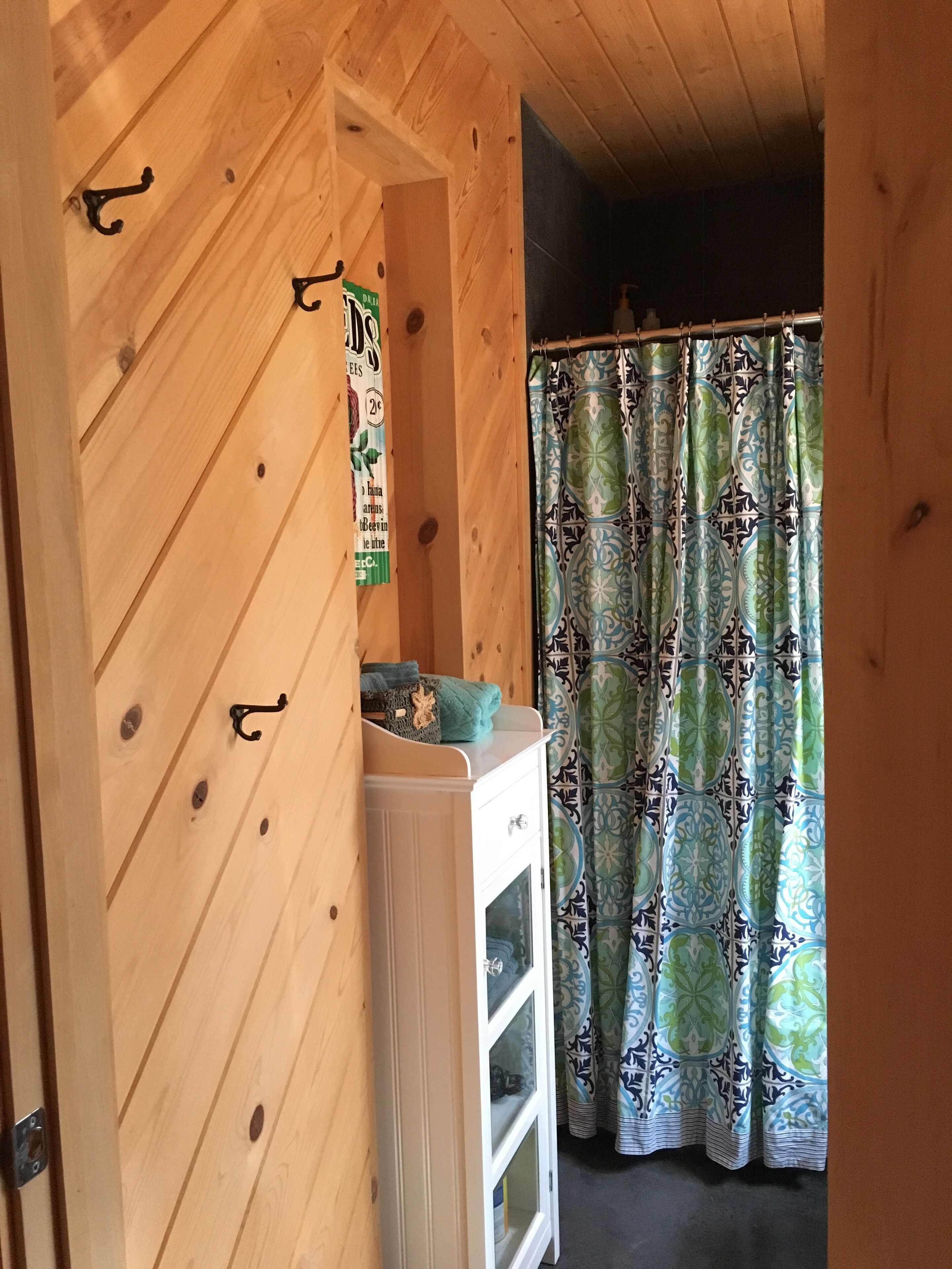Un interno in legno con un armadietto bianco, una tenda decorata e un cartello appeso al muro.