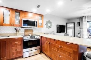 A modern kitchen with wooden cabinets, stainless steel appliances, and a large island. - 2 min walk to the beach & work from home! (Neptune Beach)