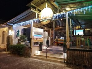 Un restaurant en plein air doté d’une entrée couverte, d’une enseigne indiquant « Pizzas et espetos », et d’un escalier menant à l’espace réservé aux clients.
