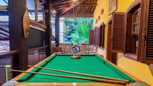 Une table de billard recouverte d’un drap vert, dotée de bandeaux en bois et offrant une vue sur un vélo à l’extérieur.