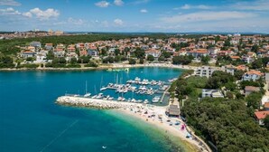 An aerial view of a coastal town with a marina, beach, and residential buildings.