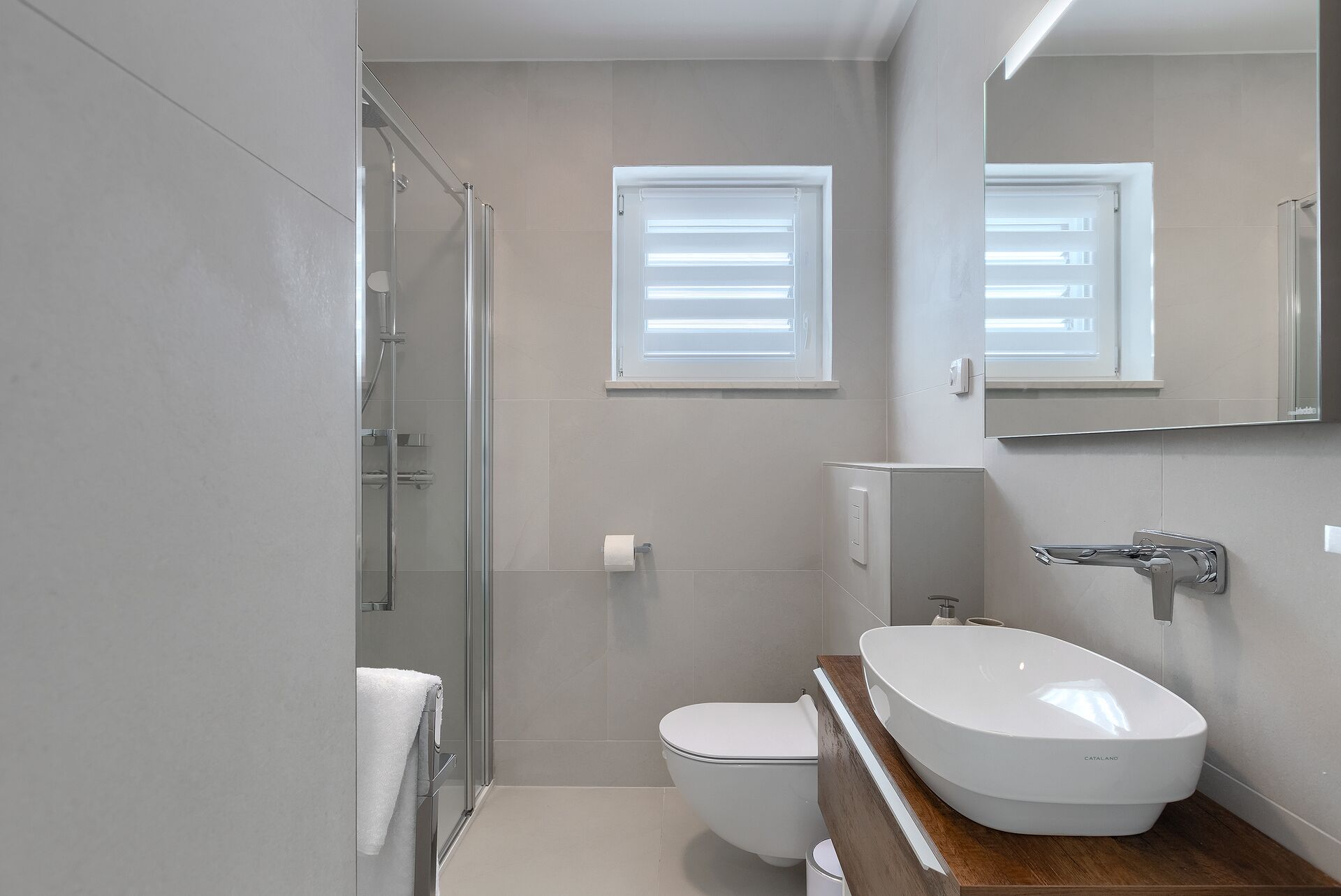 A modern bathroom with a glass shower enclosure, a toilet, and a vanity with a sink.