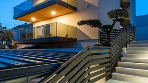 A modern multi-story building with balconies, a staircase, and a pool area.