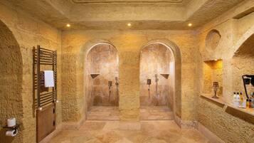 Uma área de spa com duas portas em arco, um porta-toalhas e uma prateleira com artigos de higiene pessoal.