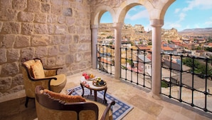 Una habitación con paredes de piedra y un balcón con vistas a un pueblo.