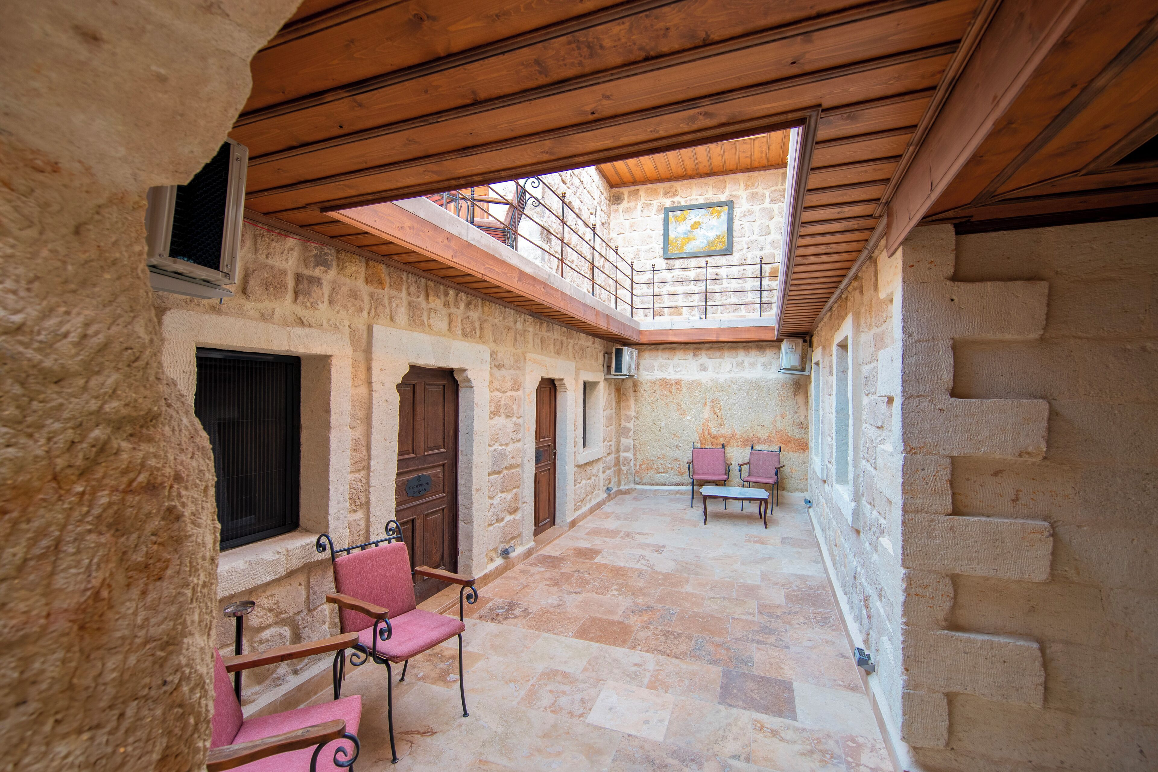 Un patio con paredes de piedra, techo de madera, una escalera y dos sillas.