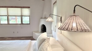 Een slaapkamer met een bed, een wandlamp en een open haard.