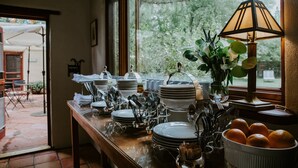 Un coin repas avec une table mise pour le repas, une fenêtre donnant sur des arbres et une lampe sur la table.