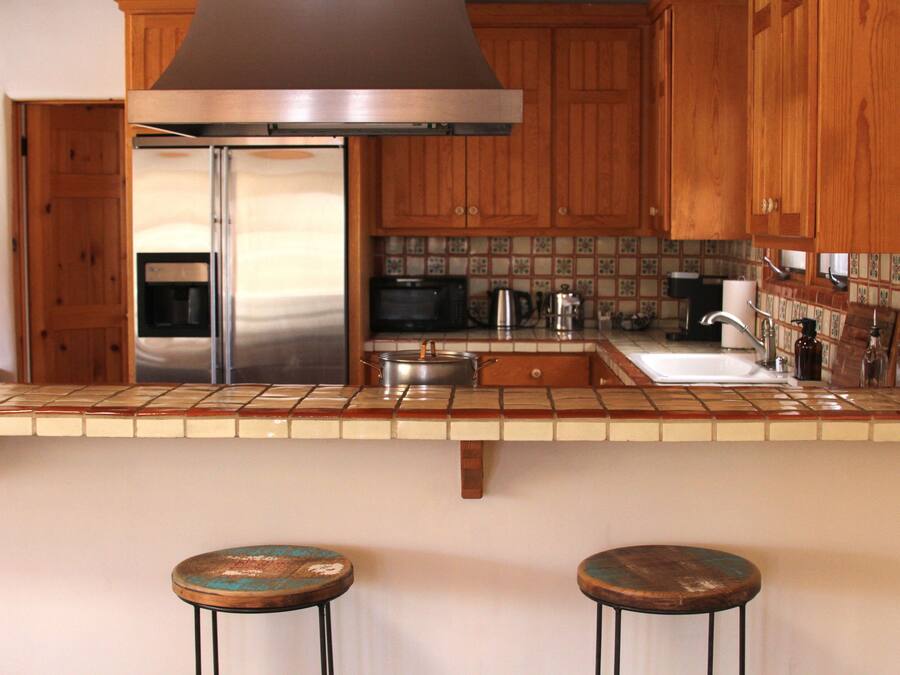 A kitchen with wooden cabinets, a stainless steel refrigerator, a microwave, and a tiled backsplash.