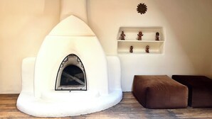 Een gezellige kamer met een witte schoorsteen, een bruine bank en een plank met decoratieve objecten.