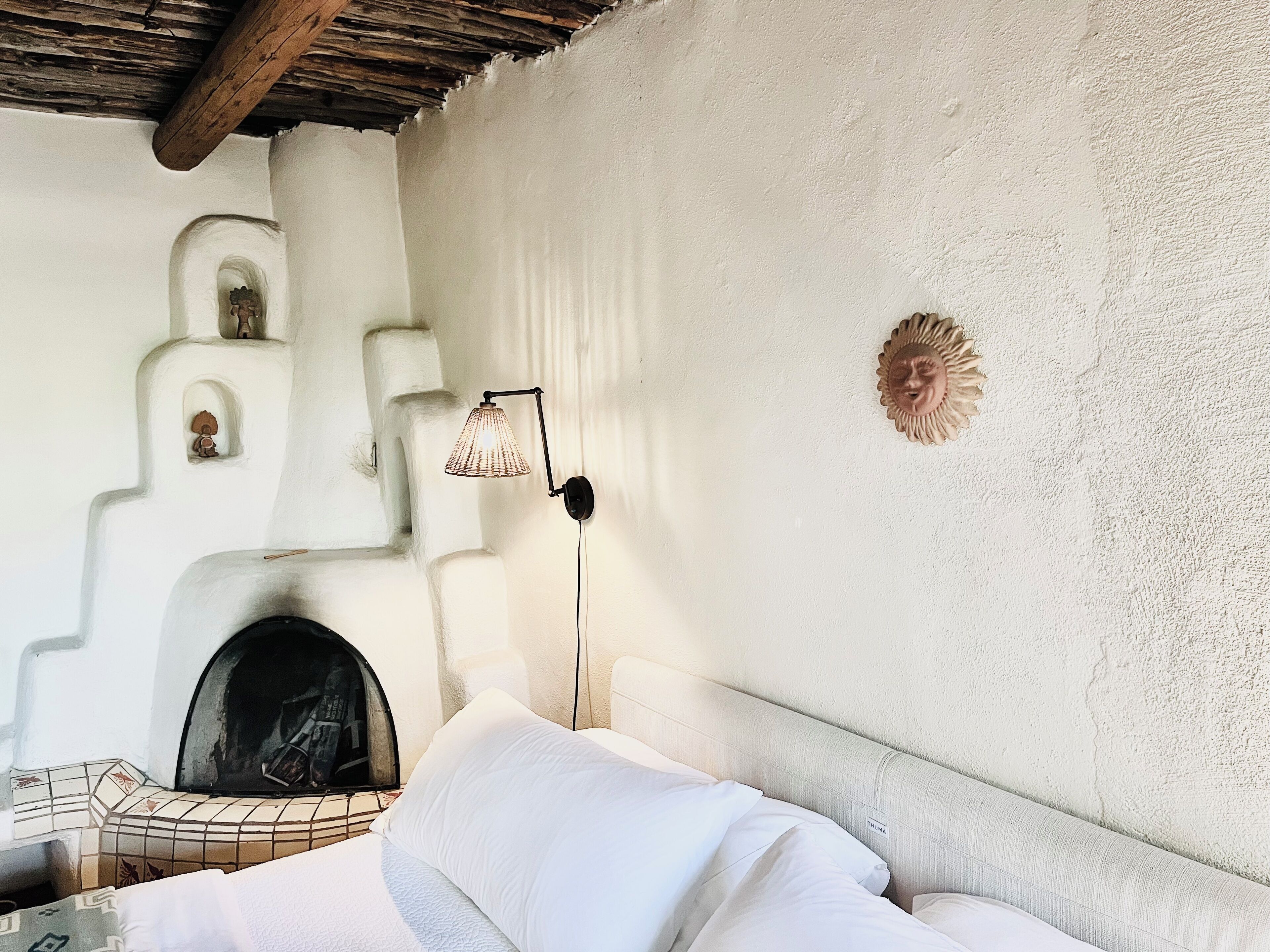 Una habitació amb un llit, una làmpada penjada a la paret i una llar de foc.