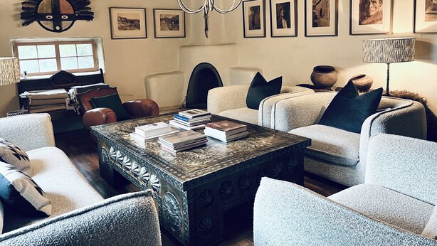 Een gezellige woonkamer met een open haard, comfortabele zitplaatsen en verschillende ingelijste foto’s aan de muur.