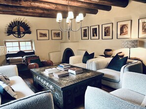 Un salon chaleureux avec une cheminée, des sièges confortables et une variété de tableaux encadrés accrochés au mur.