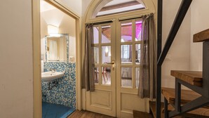 A bathroom with a sink, tiled walls, and a wooden staircase. - Florence Hideaway by Mmega (Florence)