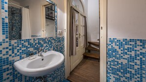 A bathroom with a white sink, blue mosaic tiles, a wooden door, and a mirror. - Florence Hideaway by Mmega (Florence)