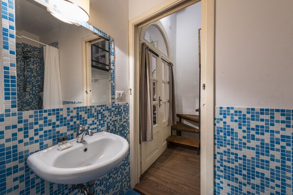 A bathroom with a white sink, blue mosaic tiles, a wooden door, and a mirror.